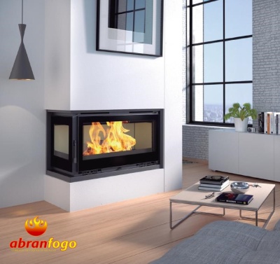Lareira embutida com estrutura preta e vidro mostrando chamas numa sala moderna com chão em madeira clara e móveis brancos