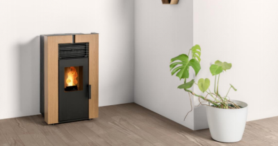 Lareira a pellets em madeira clara com planta verde em vaso branco ao lado