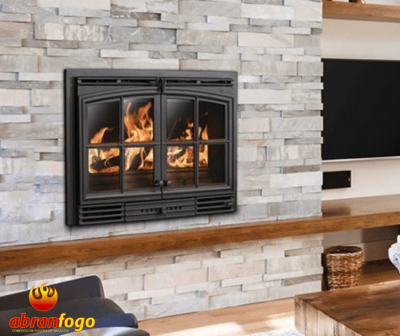 Lareira embutida de ferro preto com vidro numa parede de pedra clara