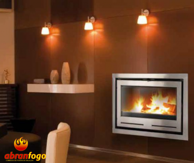 Lareira moderna embutida com moldura metálica e fogo aceso numa parede castanha com iluminação e objetos decorativos