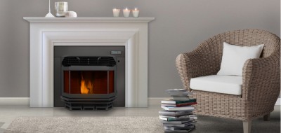 Lareira elétrica preta com moldura branca, cadeira de vime castanha com almofada branca e pilha de livros sobre tapete cinza