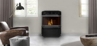 Lareira a lenha preta com chama visível numa sala moderna com poltrona de couro castanha e pufe cinzento.