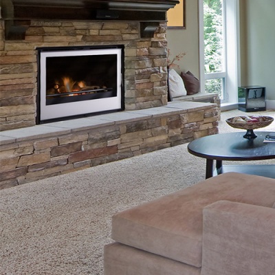 Lareira embutida numa parede de pedra com sofá e mesa de centro