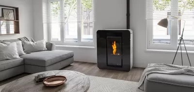 Sala de estar com sofá cinzento, lareira preta acesa e mesa redonda de madeira