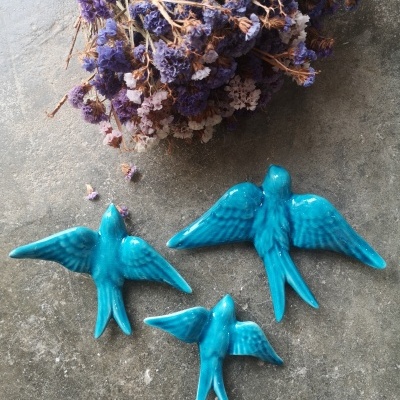 Três pássaros decorativos de cerâmica azul e flores secas