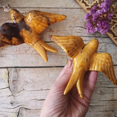 Esculturas de pássaros em âmbar em superfície de madeira com flores secas e ornamento