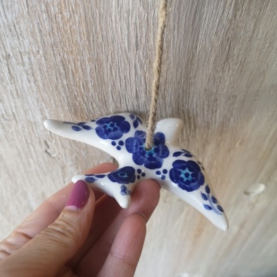 Ornamento cerâmico em forma de arraia com padrões florais azuis pendurado
