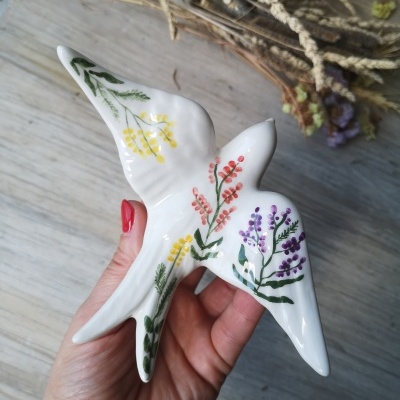 Figura de cerâmica branca em forma de pássaro com pintura floral colorida