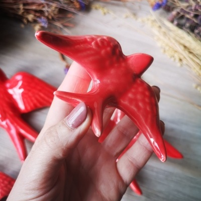 Pássaro decorativo vermelho em cerâmica segurado numa mão