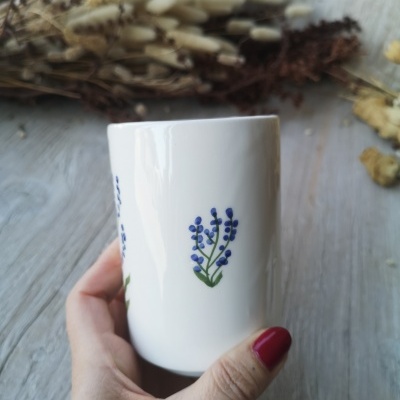Caneca branca com desenho de ramo de flores azuis e folhas verdes
