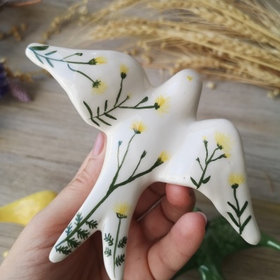 Escultura de pássaro branco com flores amarelas pintadas