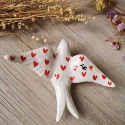 Figura cerâmica branca em forma de pássaro com corações vermelhos e palavra Tio