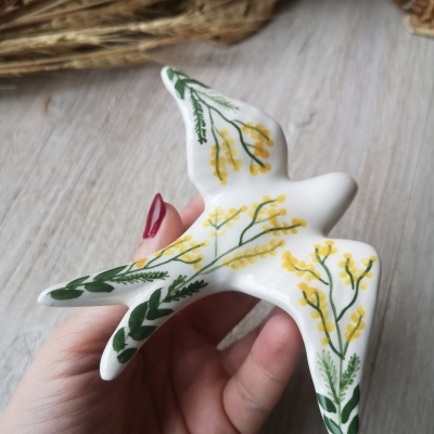 Pássaro decorativo branco em cerâmica com pintura de flores amarelas e folhas verdes