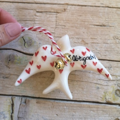 Enfeite de pássaro branco com corações vermelhos e texto 'Obrigado!' em madeira rústica