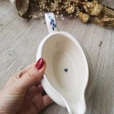 Prato de cerâmica branco com decoração azul e flores secas ao fundo