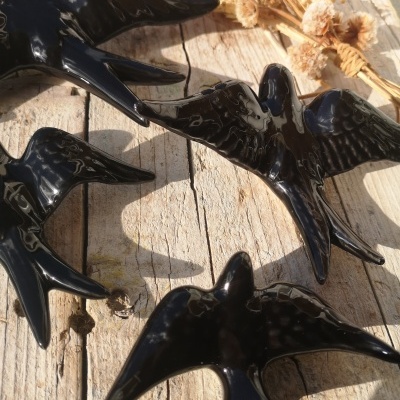 quatro pássaros decorativos pretos brilhantes sobre madeira envelhecida com flores secas