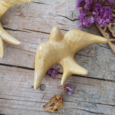 Objeto decorativo em madeira clara com formato orgânico sobre superfície de madeira rústica com flores secas roxas