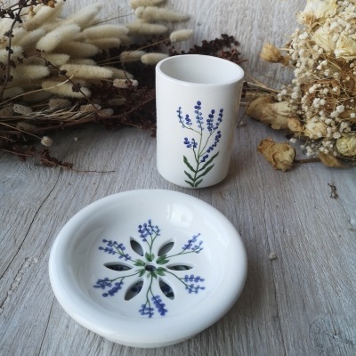 Conjunto cerâmico com copo e prato decorados com flores azuis em fundo de madeira