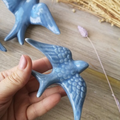 Duas aves decorativas azuis em cerâmica com acabamento brilhante sobre madeira clara
