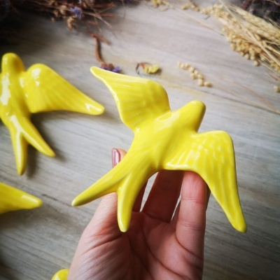 Pássaros decorativos amarelos em cerâmica sobre fundo de madeira