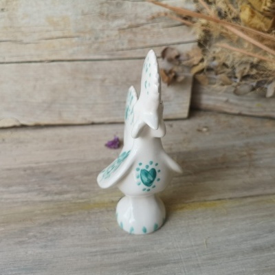 Figurinha de pássaro em cerâmica branca com detalhes verdes e corações