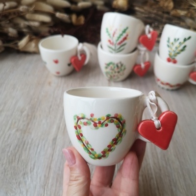Pequena chávena branca com coração pintado e pendente vermelho na pega