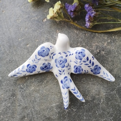 Pássaro decorativo em cerâmica branca com flores azuis