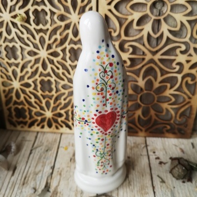 Figurinha de cerâmica branca com padrão de pontos coloridos e coração vermelho