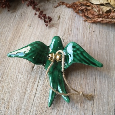 Pendurador cerâmico verde em forma de pássaro com corda, sobre madeira clara