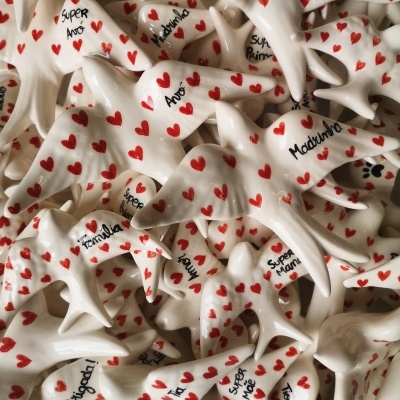 Grilos de cerâmica branca com corações vermelhos e textos escritos à mão