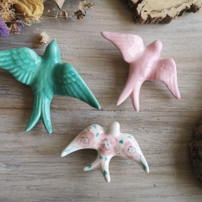 Figuras decorativas de pássaros em cerâmica colorida sobre madeira