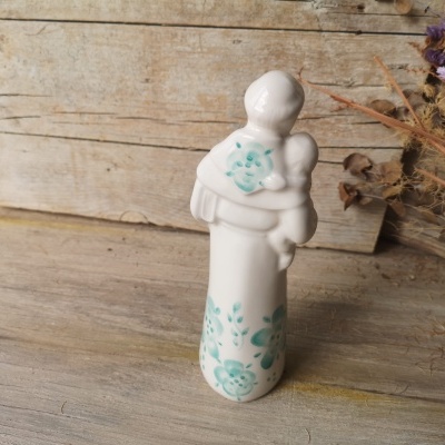 Estatueta cerâmica branca decorada com flores azuis numa superfície de madeira