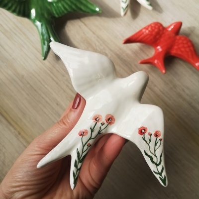 Pássaros decorativos em cerâmica com padrões florais e texturas brilhantes.