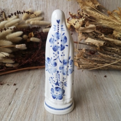 Estátua de porcelana branca com flores azuis em fundo de madeira e ramos secos