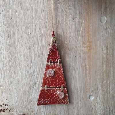 Suspensão decorativa triangular vermelha texturizada com botões, pendurada em madeira clara.