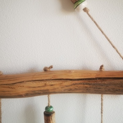 Móbile decorativo em madeira, corda e contas cerâmicas pendurado na parede