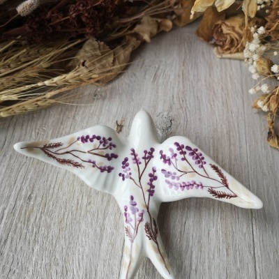 Prato decorativo em cerâmica branca com pintura floral em forma de pássaro.