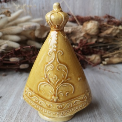 Estatueta de cerâmica amarela com padrão em relevo sobre superfície de madeira