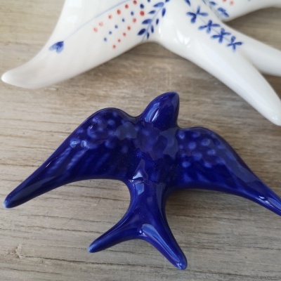 Figuras decorativas azuis e brancas de pássaros em cerâmica sobre madeira