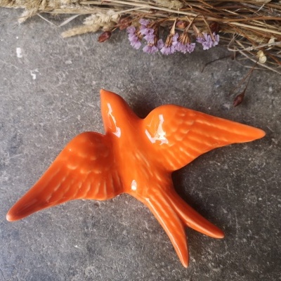 Pássaro decorativo laranja em cerâmica com asas abertas