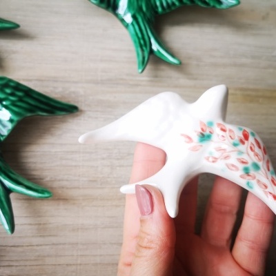 Figura decorativa branca em forma de pássaro com detalhes florais