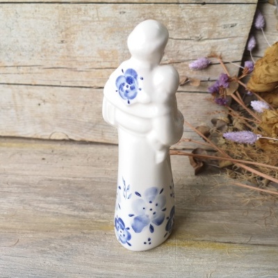 Figura decorativa de porcelana branca com padrão floral azul representando mãe a segurar bebé