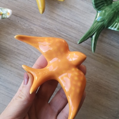 Pássaro decorativo cerâmico laranja segurado à mão