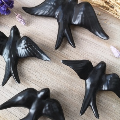 Figuras decorativas de pássaros pretos sobre mesa de madeira com flores secas