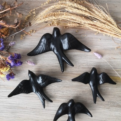 Figuras decorativas pretas de pássaros em madeira clara com flores secas