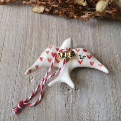 Figura em cerâmica branca com corações vermelhos, sinos dourados e cordão vermelho e branco