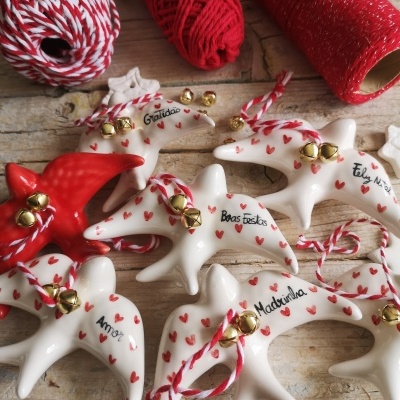Estrelas de cerâmica decorativas com palavras e sinos, ao lado de rolos de fio