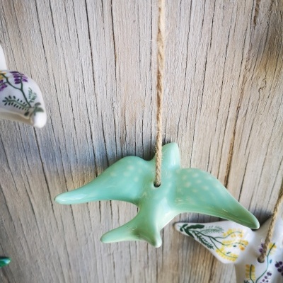 Móbile com passarinhos em cerâmica pendurados numa parede de madeira.