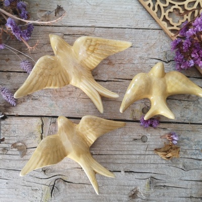 Esculturas de pássaros em madeira sobre mesa rústica com flores secas lilases