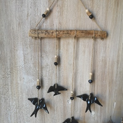Móbile decorativo com pássaros pretos em cerâmica pendurado em madeira rústica